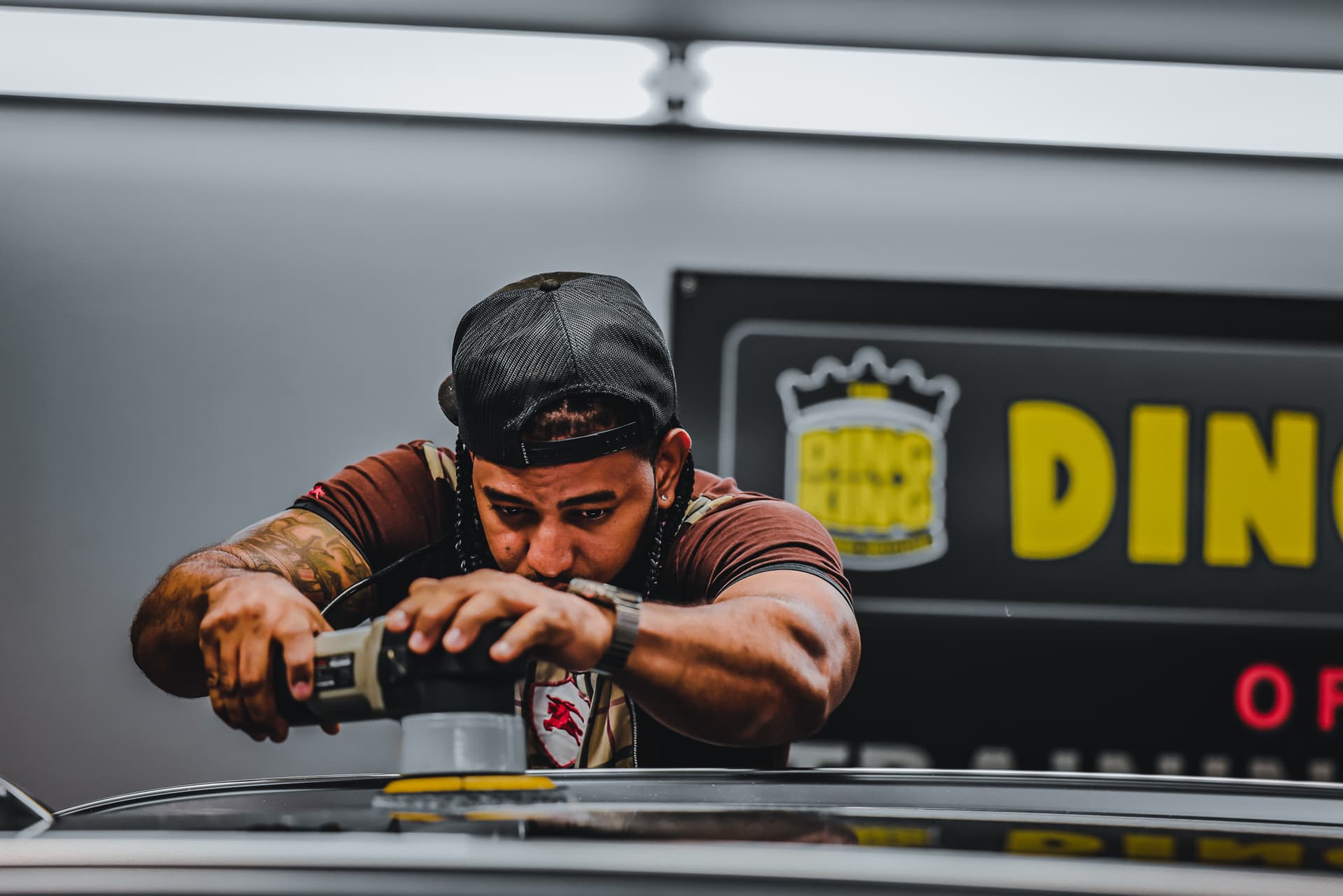 A technician machine-polishing a vehicle panel during paint correction